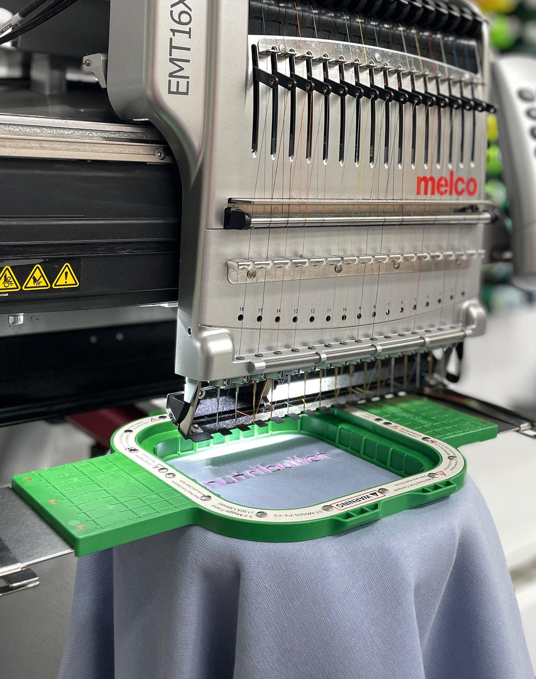Garment secured in an embroidery hoop ready for stitching on branded clothing