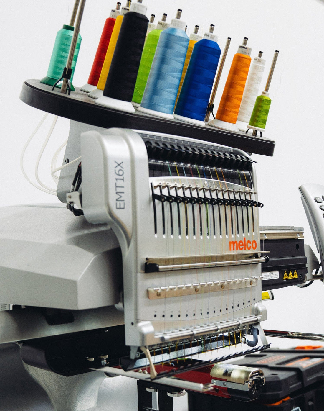 Embroidery machine stitching a logo onto apparel using coloured threads